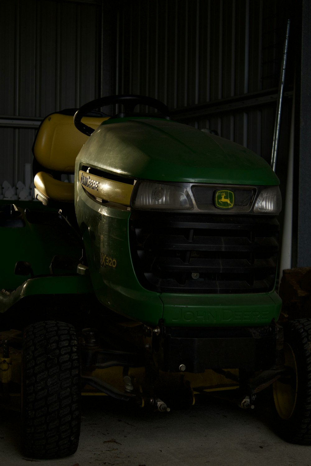 a green lawn tractor parked in a garage