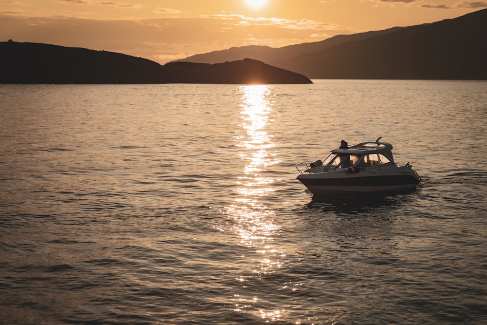 a small boat in the middle of the ocean at sunset