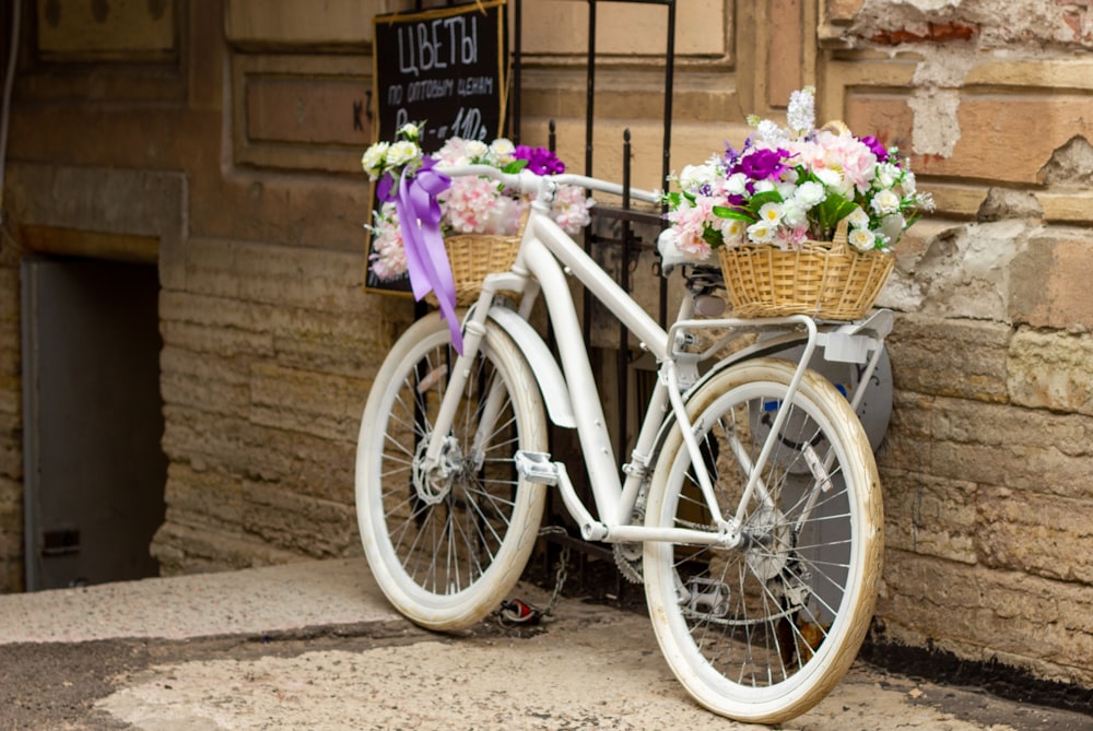 a white bicycle with baskets of flowers on the front