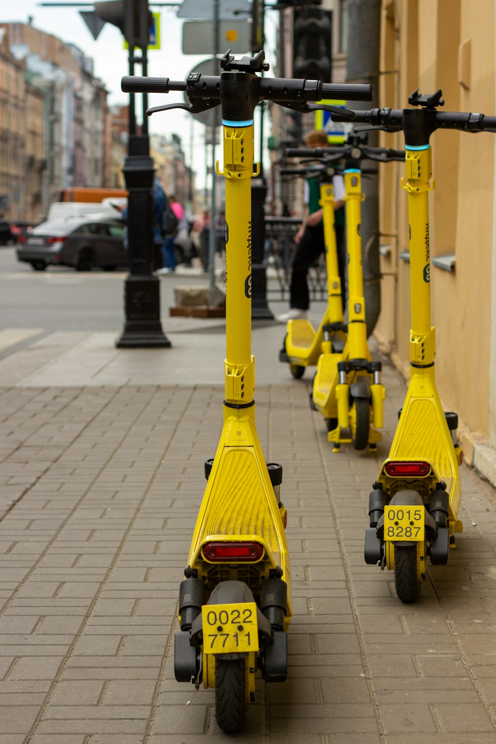 a row of yellow scooters parked on the side of a street