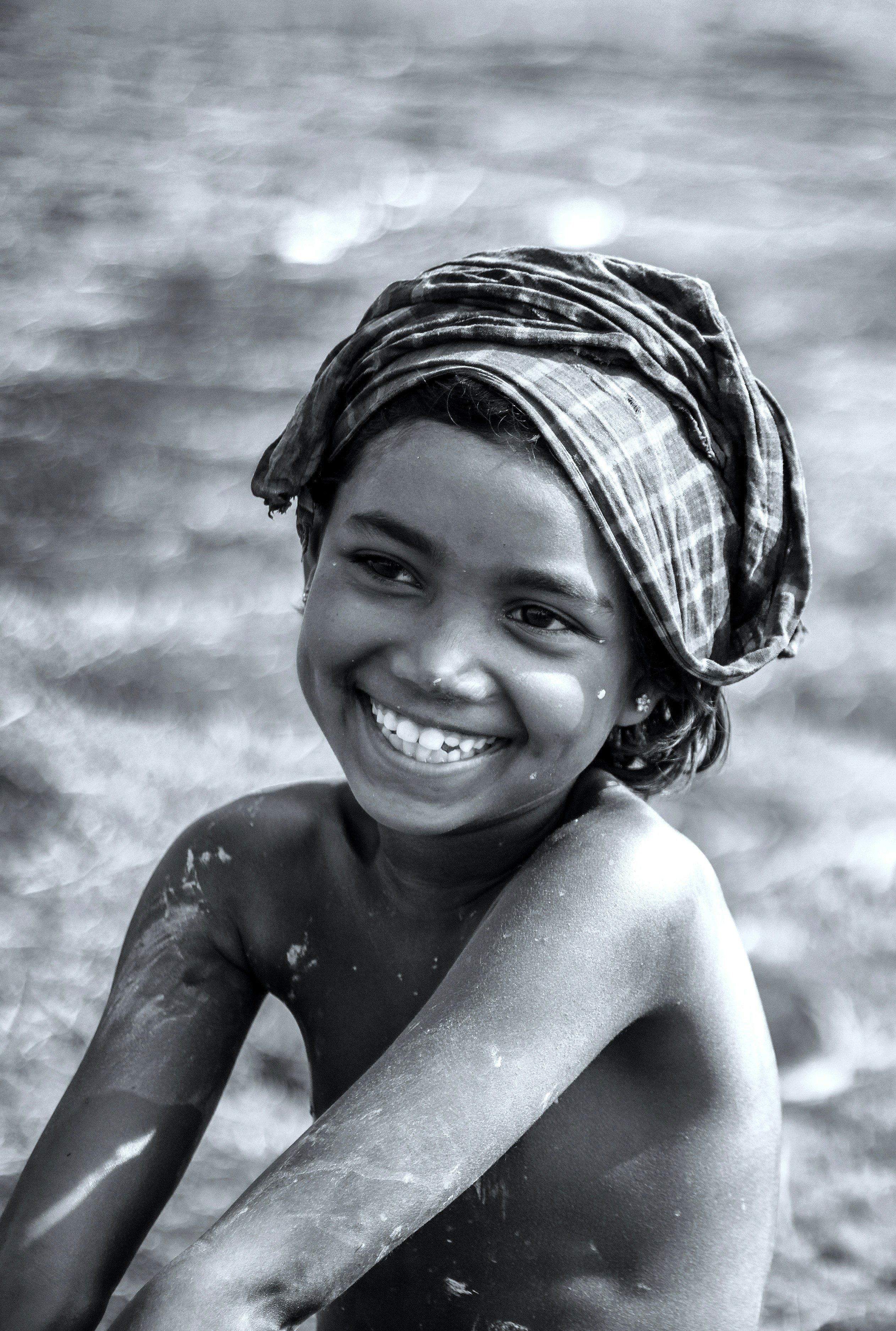 a young girl smiles while sitting in the water