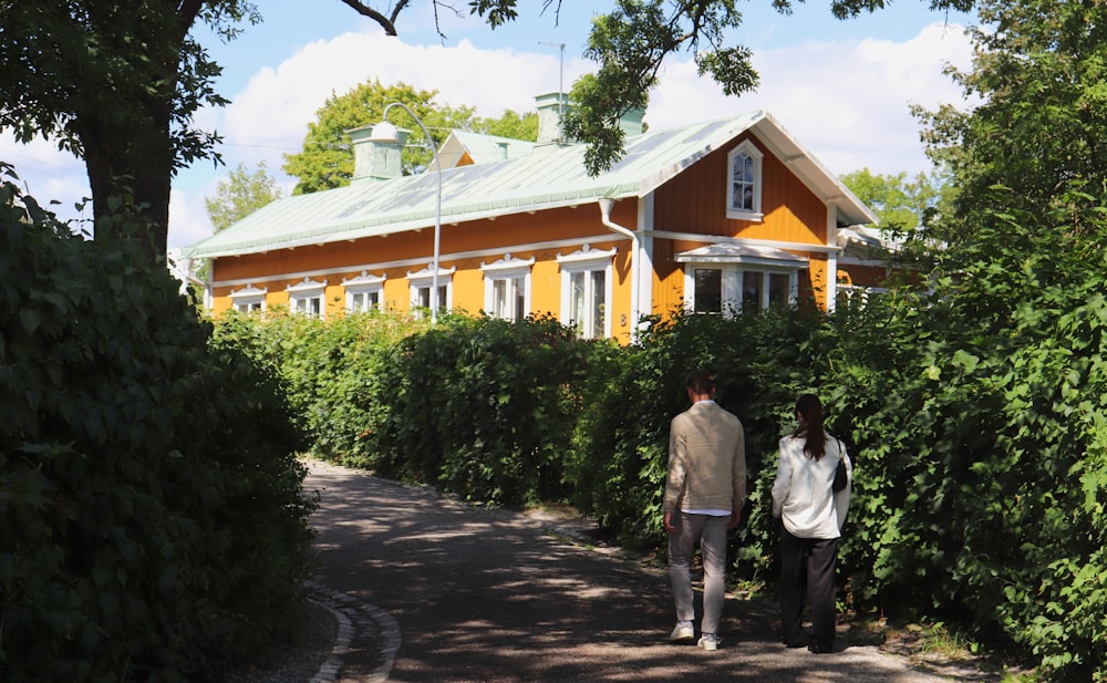 a man and a woman walking down a path in front of a yellow house