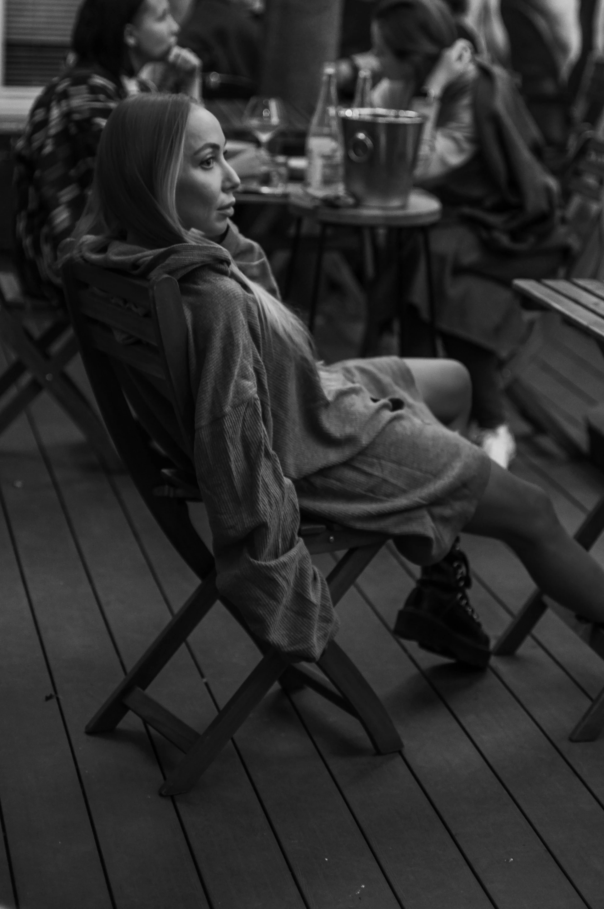 A candid shot of a woman sitting at a café table, dressed in a chic, relaxed outfit with colors blending harmoniously with the #4a413c and #ddb6b0 hues.