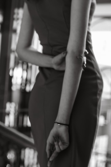 Black and white photo of a model wearing a sleek, modern outfit from cuts, standing against a minimalist urban backdrop.
