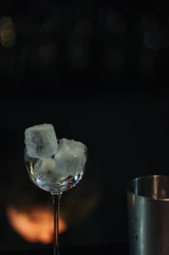 Close-up of a crystal-clear cocktail shaker mid-pour, catching the light with a splash of golden liquid.