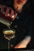 Bartender expertly pouring a signature Booze House liquor into a crystal glass with a golden rim.