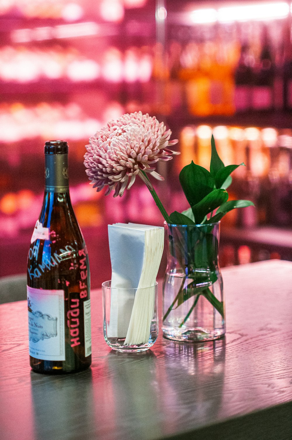 a bottle of beer and a vase of flowers on a table