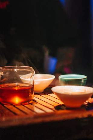 Cozy cafe interior with warm lighting and inviting tea setup on a wooden table.