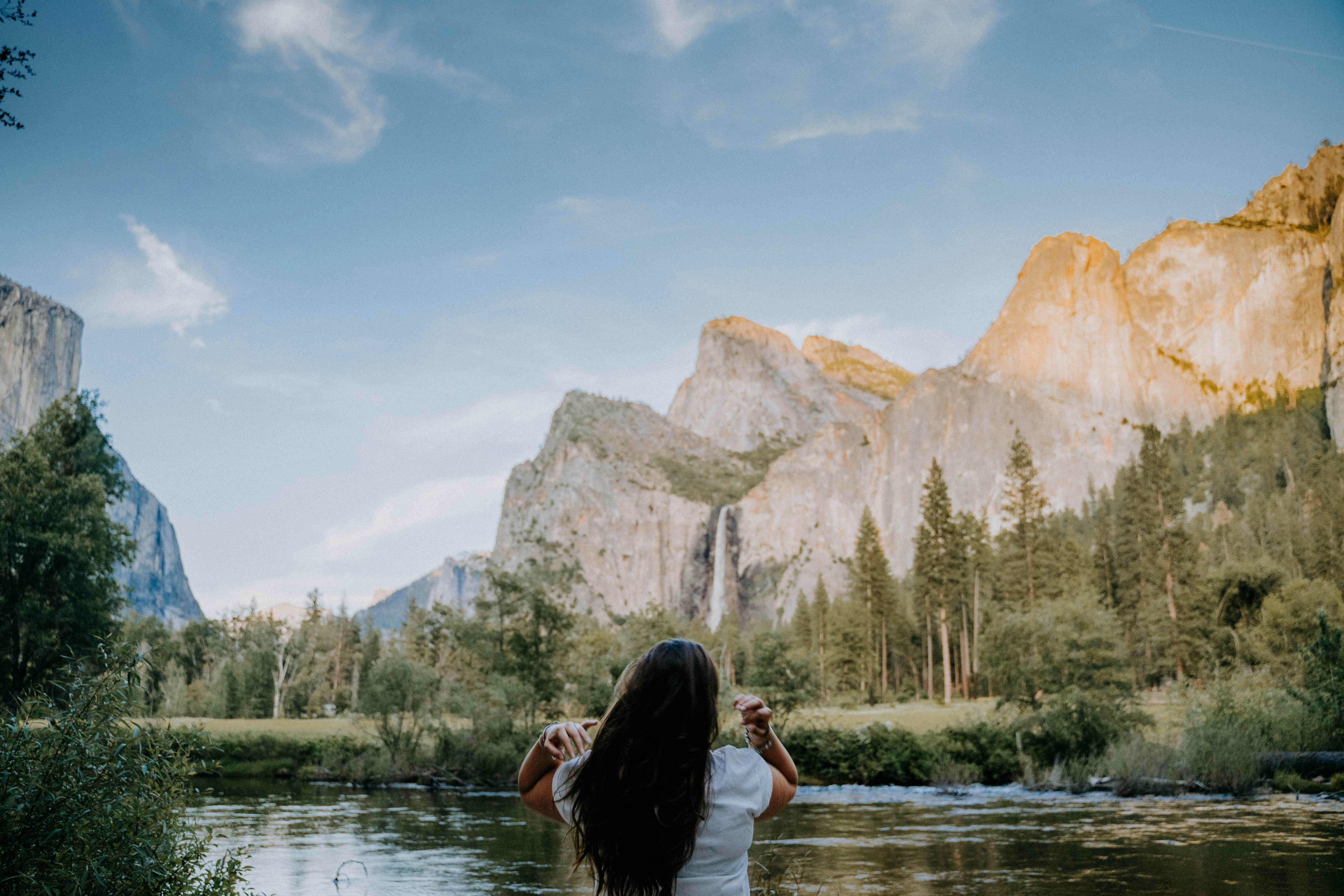 Una mujer parada frente a un río con montañas al fondo
