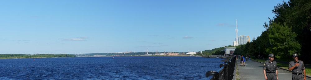 a group of people riding bikes down a sidewalk next to a body of water