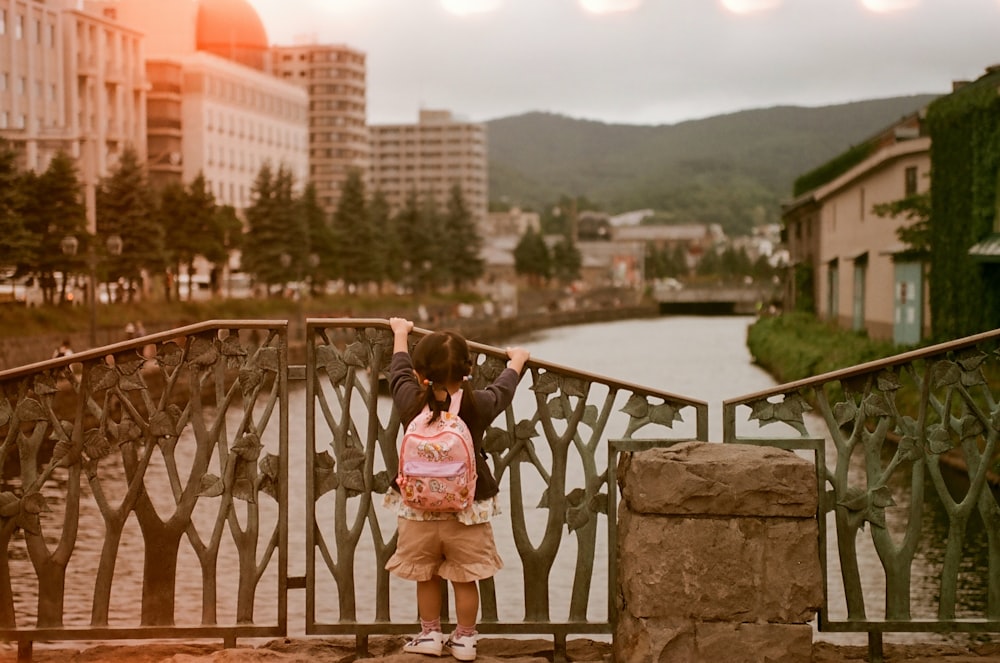 a little girl that is standing on a bridge