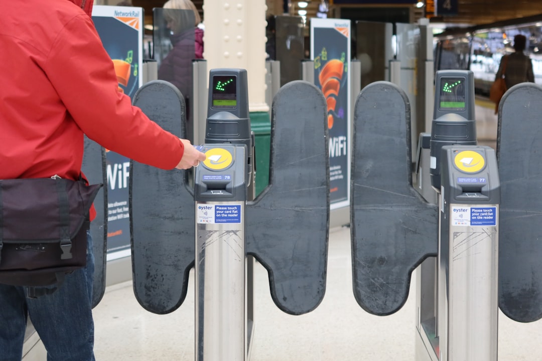 Commuter tapping card at train station ticket barrier