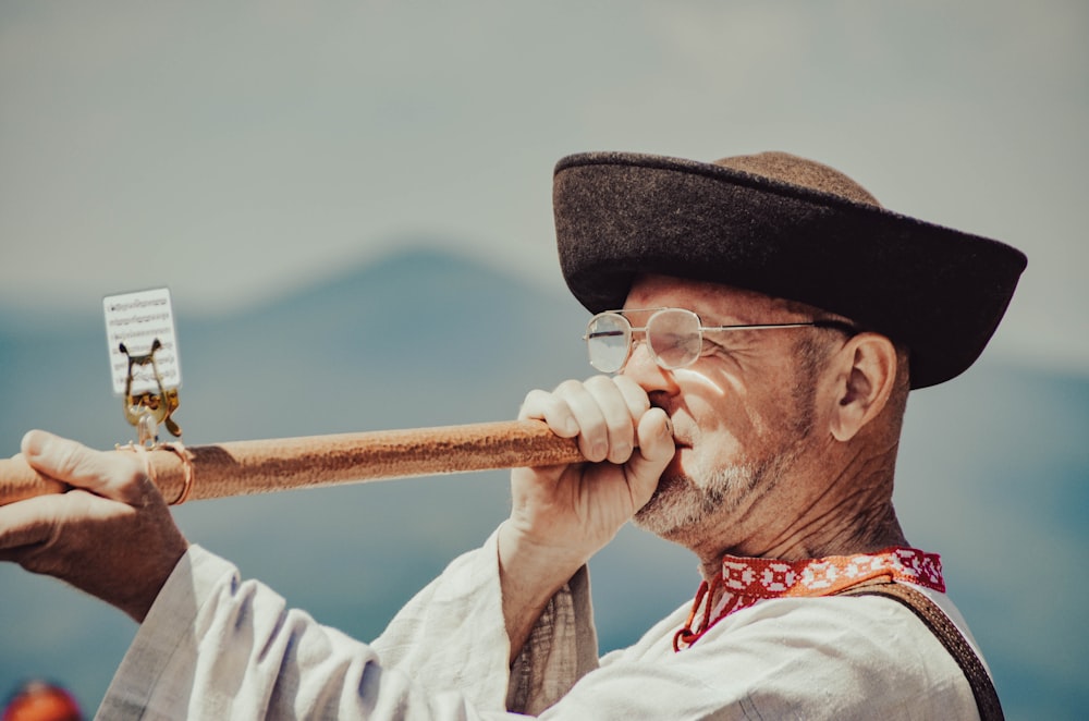 a man wearing a hat and glasses playing a flute