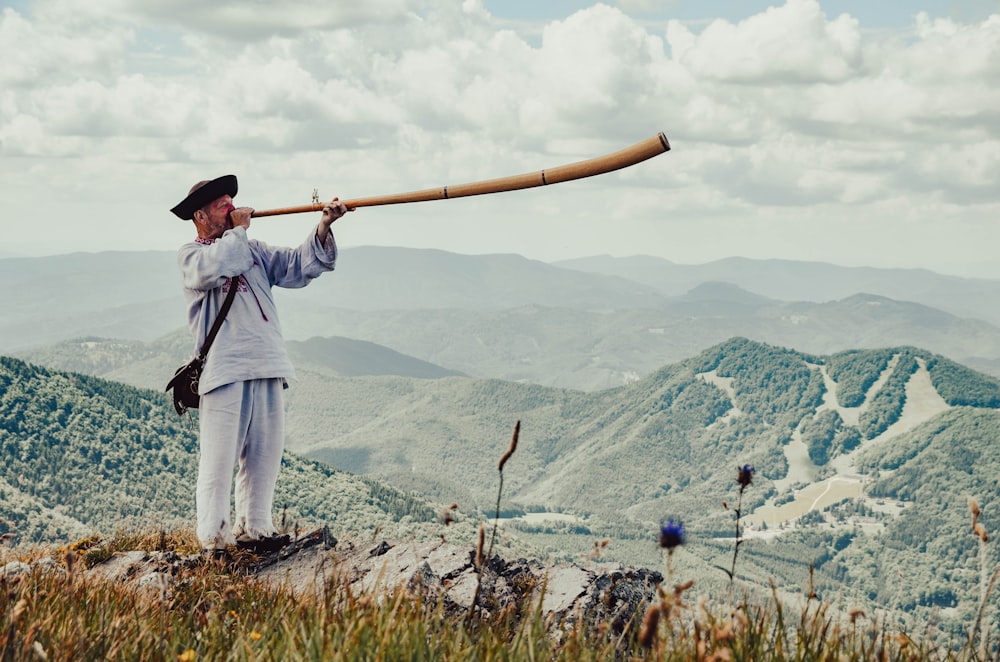 a man holding a baseball bat on top of a hill
