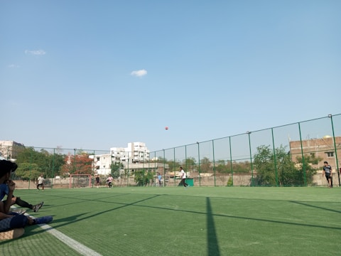 A group of people playing team sports on a sunny field.