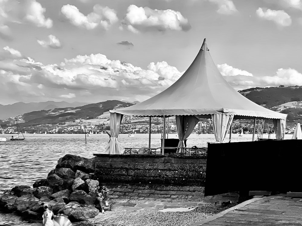 a white tent sitting next to a body of water