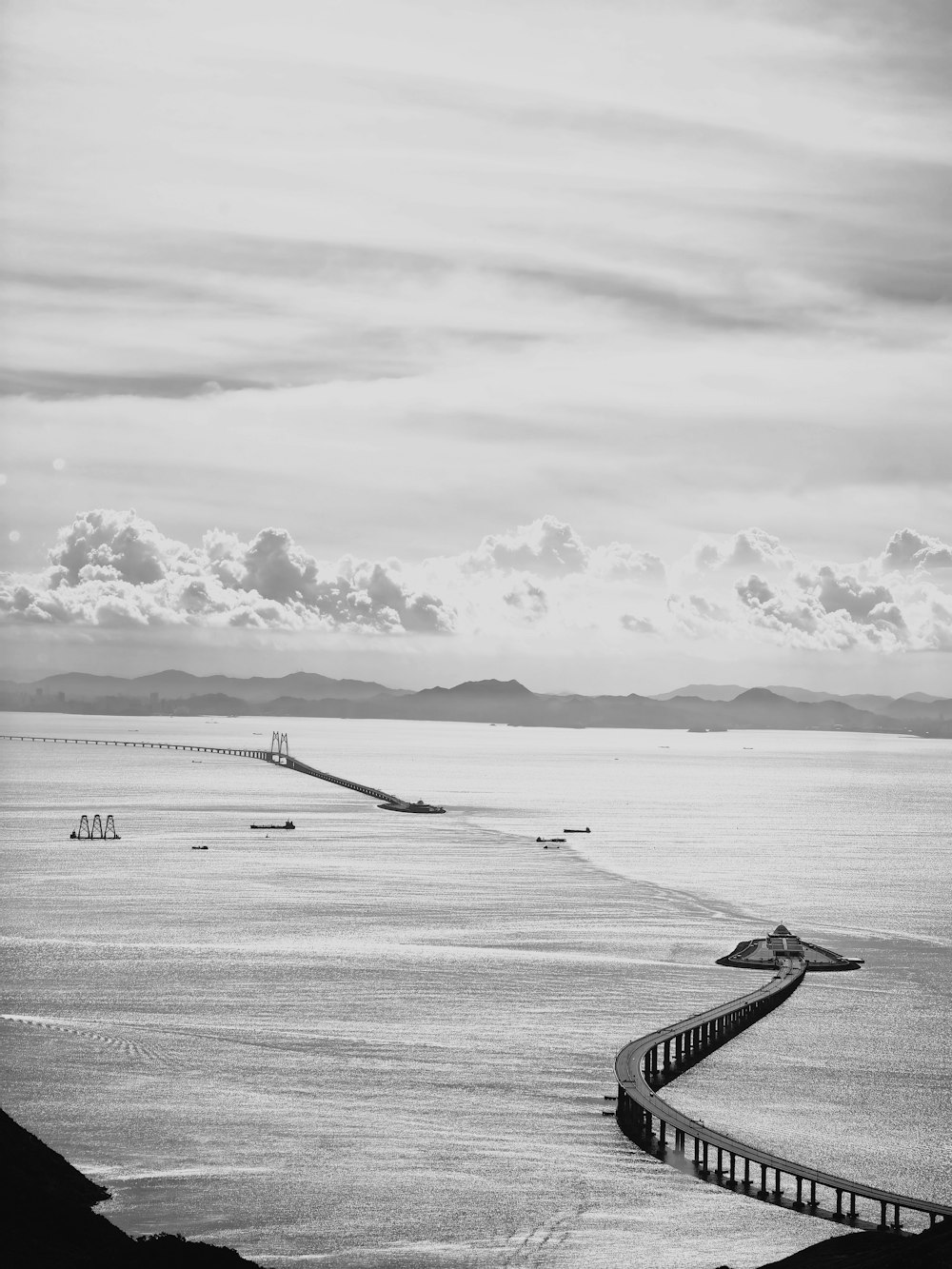 a black and white photo of the ocean and a bridge