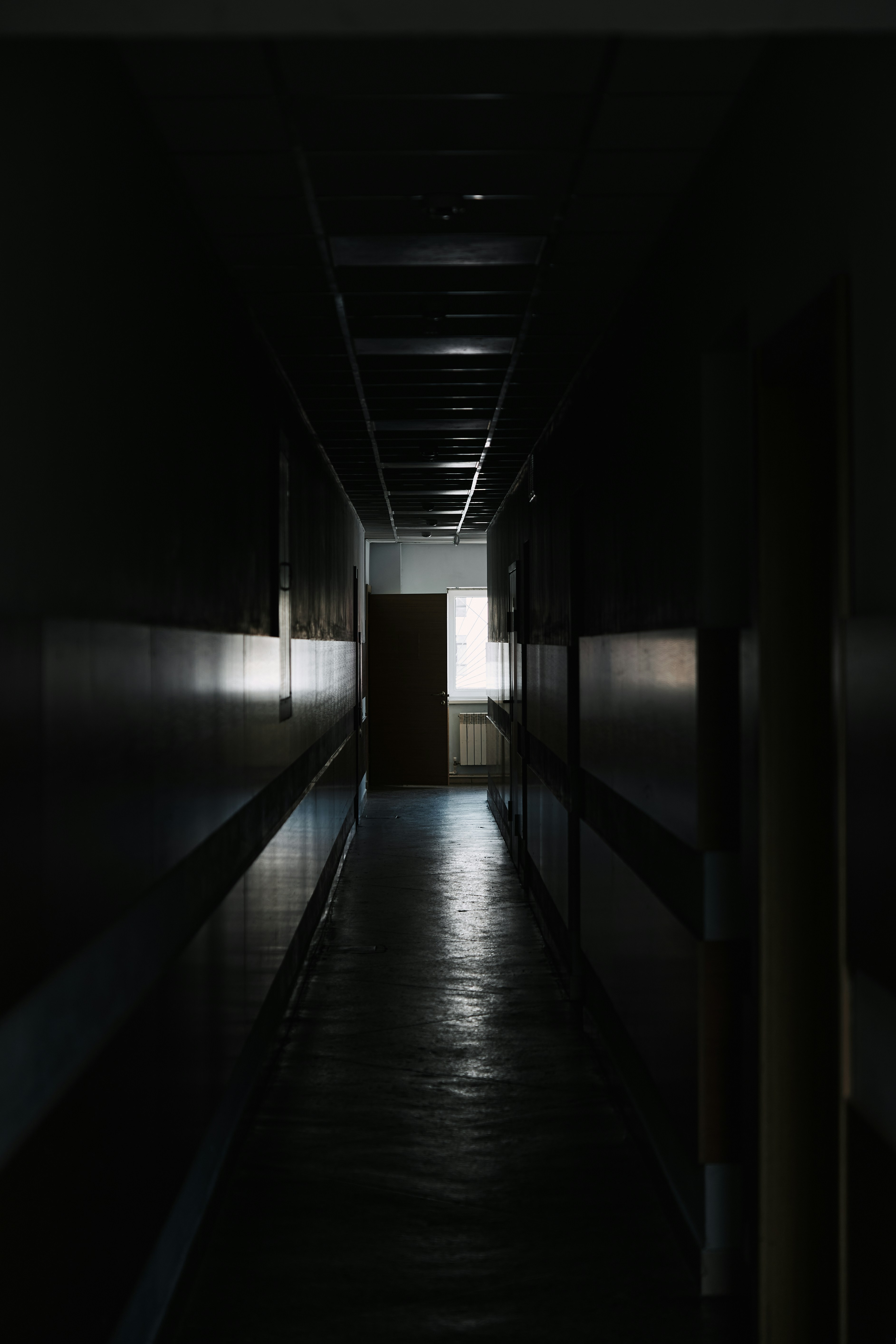 Ein langer, dunkler Flur mit einer Tür, die zu einem anderen Raum führt  Foto – Kostenloses Bild zum Thema Schulflur auf Unsplash, image size:3000x4500