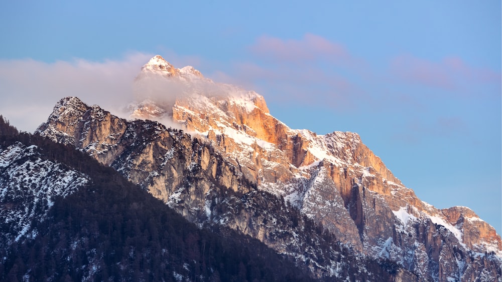 a snow covered mountain with a cloud in the sky