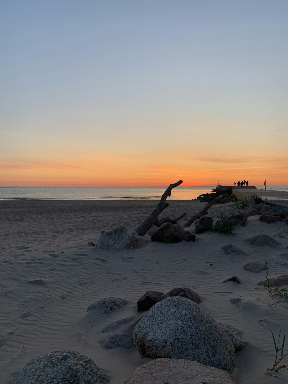 the sun is setting on the beach with rocks