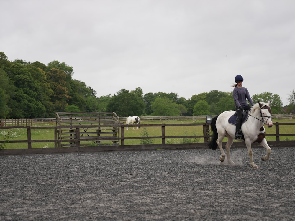 a woman riding on the back of a white horse