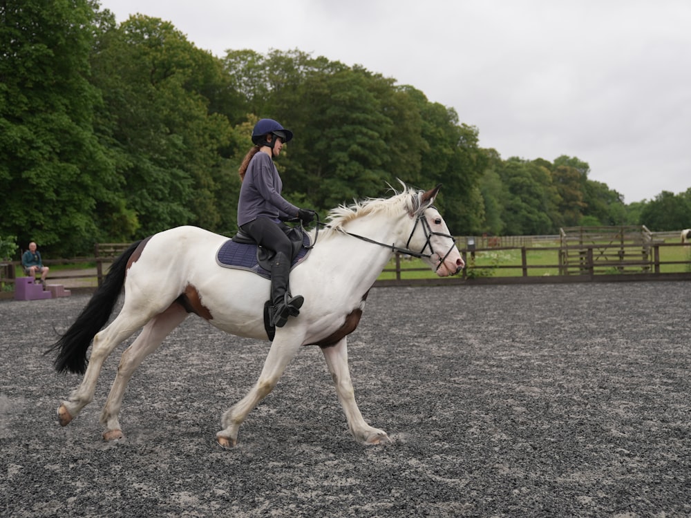 a woman riding on the back of a white horse