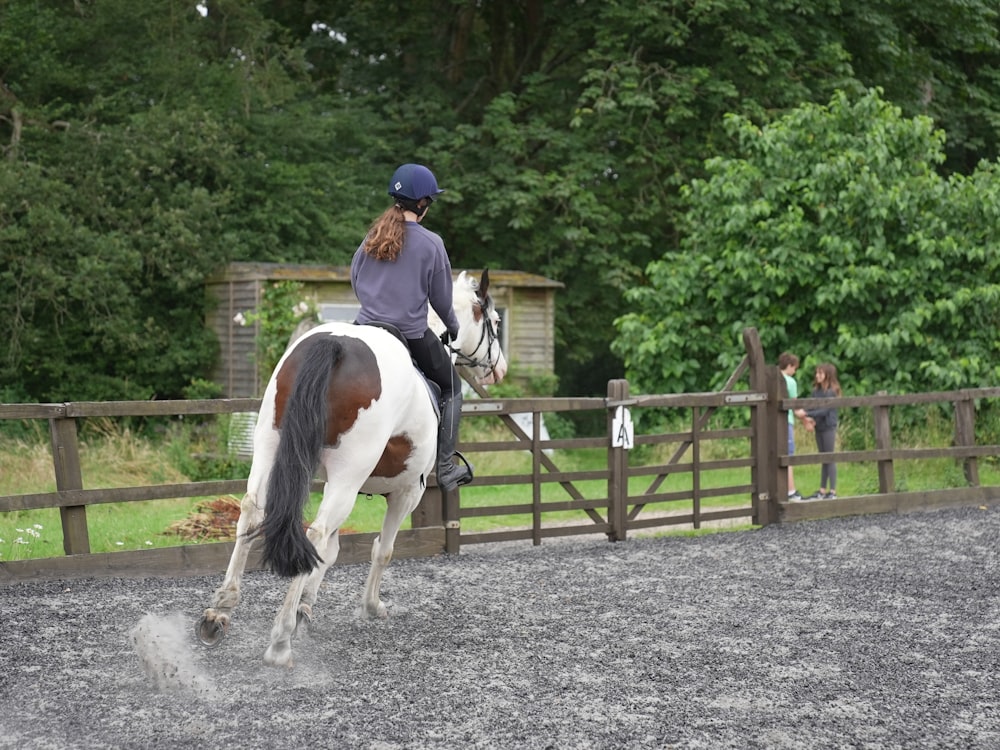 a woman riding on the back of a white and brown horse