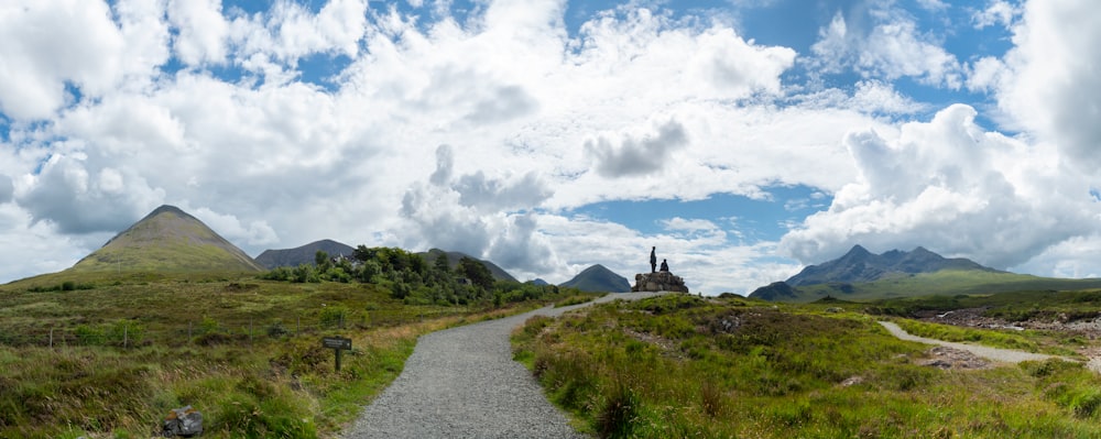 Un camino que conduce a una montaña con un cielo lleno de nubes