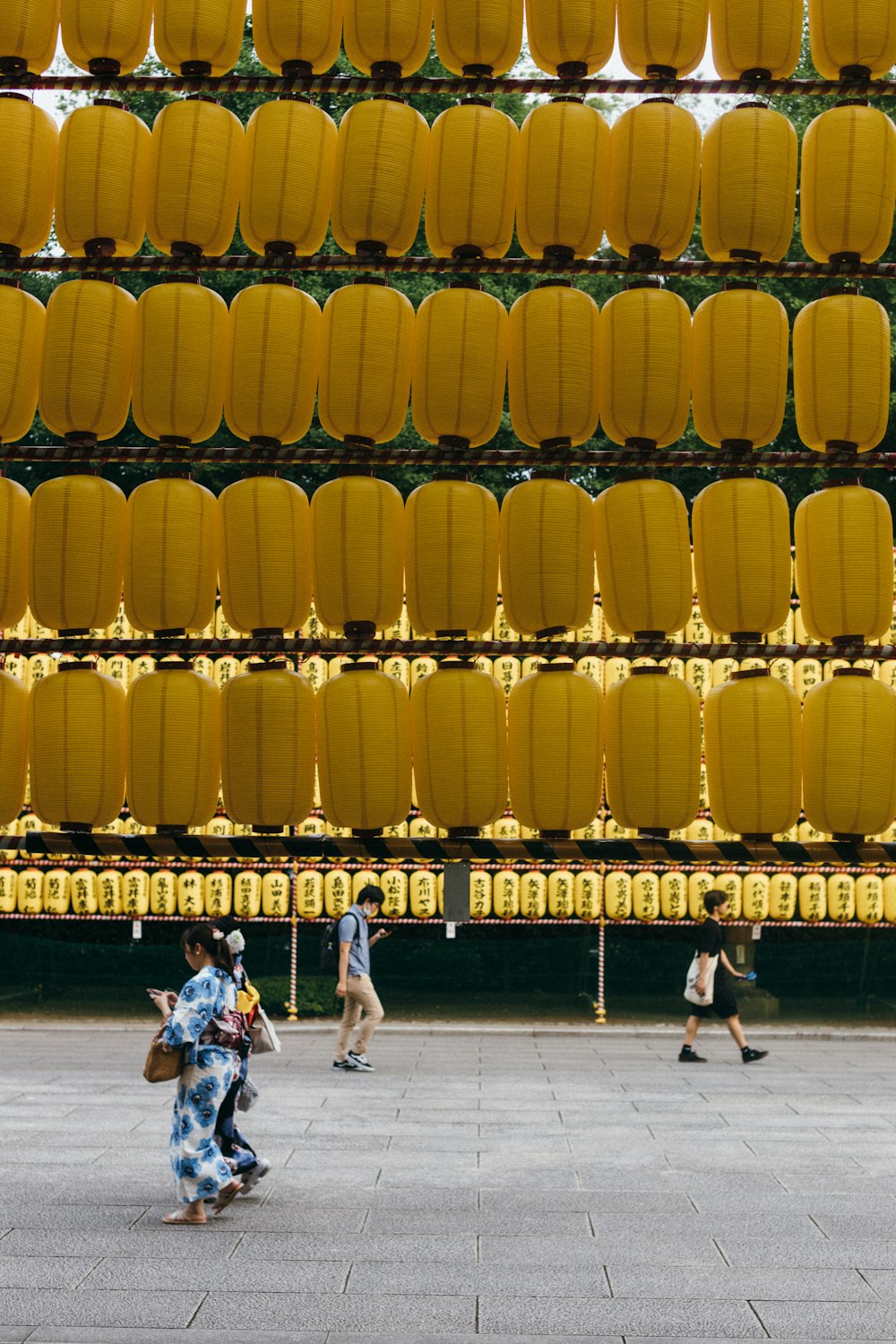a group of people walking down a street next to a yellow wall