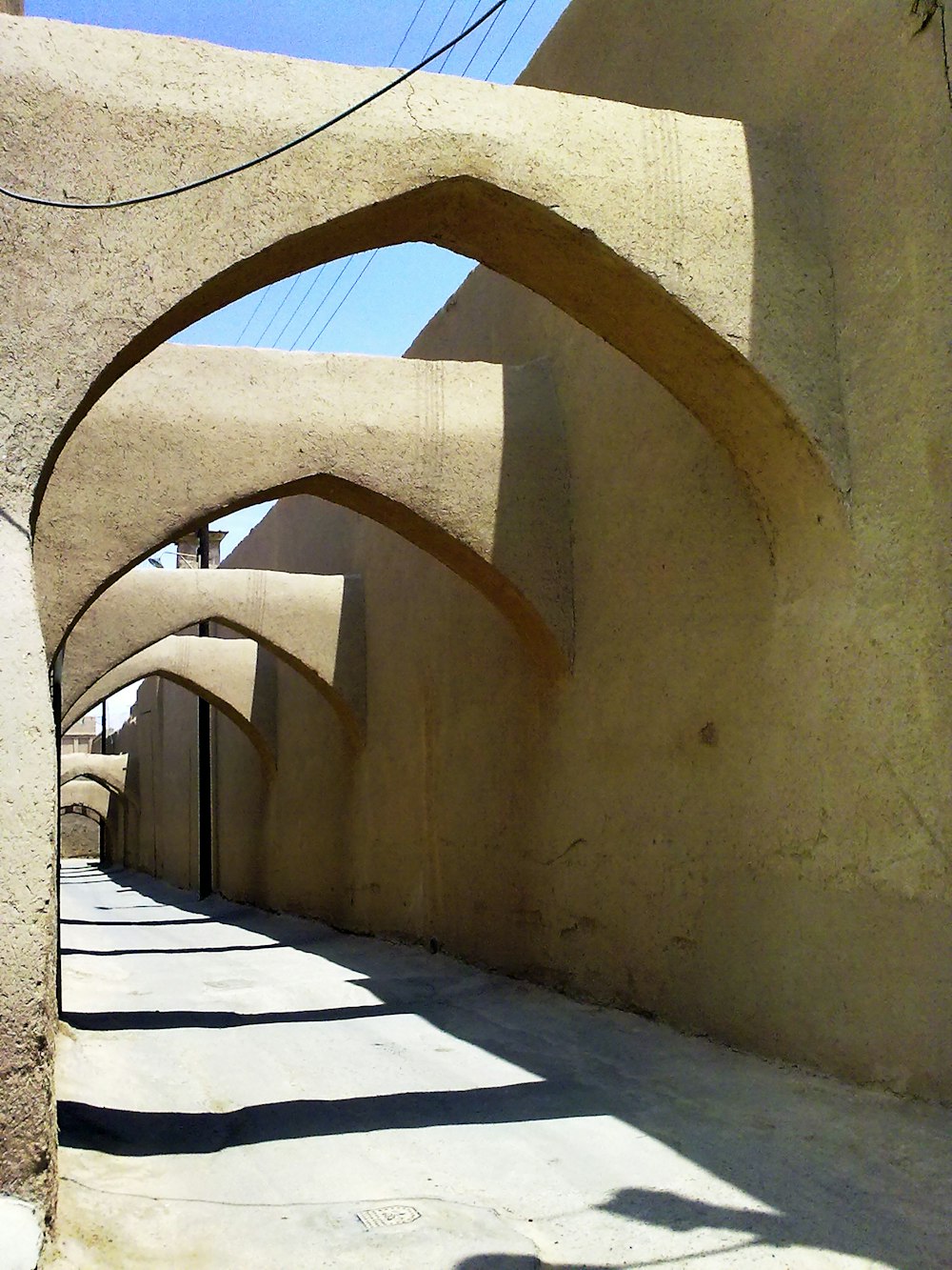 a street lined with arches and buildings under a blue sky