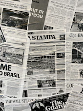 The image contains a collage of various international newspaper front pages, featuring headlines and images related to global news events. The papers have sections in different languages such as English, Italian, and Hebrew. Prominent topics include political issues and events, with accompanying black-and-white photographs.