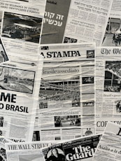 The image contains a collage of various international newspaper front pages, featuring headlines and images related to global news events. The papers have sections in different languages such as English, Italian, and Hebrew. Prominent topics include political issues and events, with accompanying black-and-white photographs.