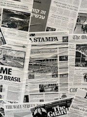 The image contains a collage of various international newspaper front pages, featuring headlines and images related to global news events. The papers have sections in different languages such as English, Italian, and Hebrew. Prominent topics include political issues and events, with accompanying black-and-white photographs.