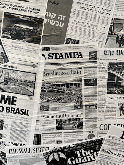 The image contains a collage of various international newspaper front pages, featuring headlines and images related to global news events. The papers have sections in different languages such as English, Italian, and Hebrew. Prominent topics include political issues and events, with accompanying black-and-white photographs.
