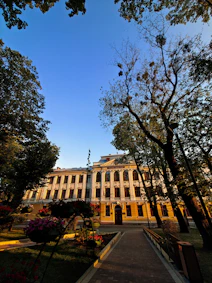 a large building with trees and flowers in front of it