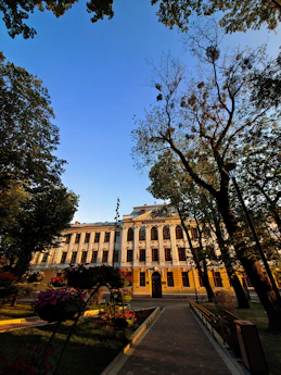 a large building with trees and flowers in front of it