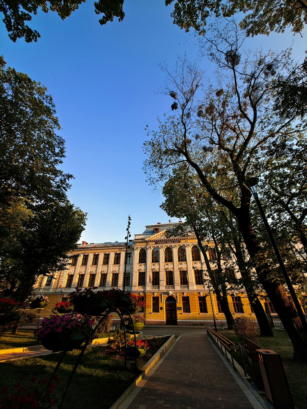 a large building with trees and flowers in front of it