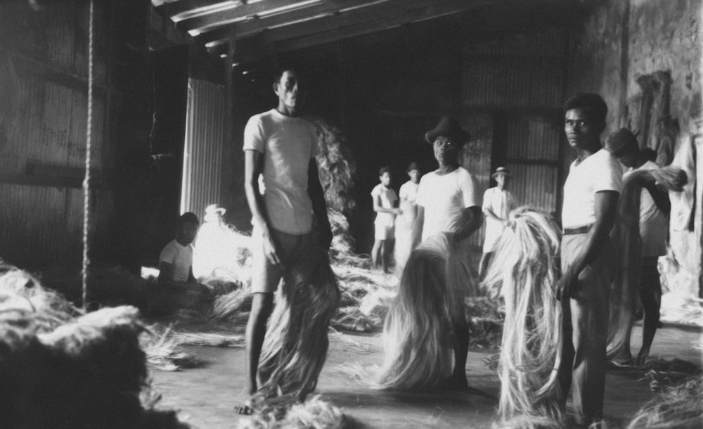 a black and white photo of a group of people in a barn