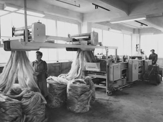 a black and white photo of men working in a factory