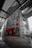 A large mural on a concrete wall depicts a figure wearing a number 14 jersey, standing and pointing. The mural features a red and black color scheme with distinctive white crosses. The surroundings are industrial with metallic structures and geometric designs, creating an urban atmosphere.