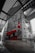 A large mural on a concrete wall depicts a figure wearing a number 14 jersey, standing and pointing. The mural features a red and black color scheme with distinctive white crosses. The surroundings are industrial with metallic structures and geometric designs, creating an urban atmosphere.