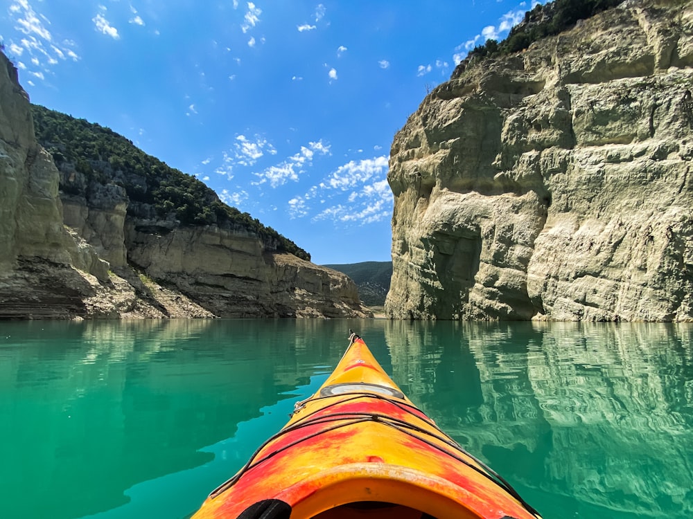 a kayak in the middle of a lake with cliffs in the background