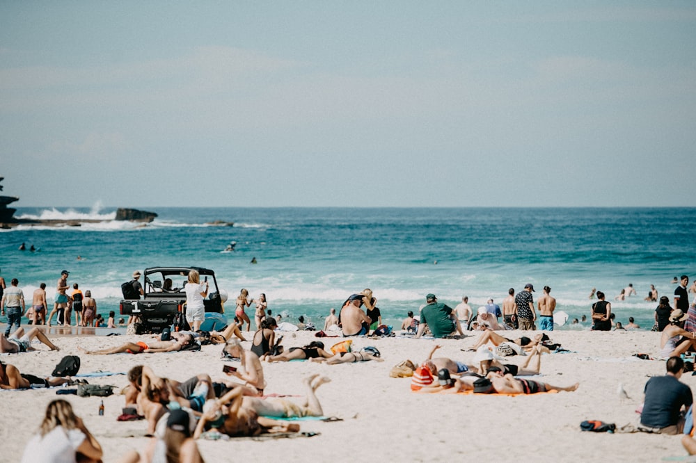 a crowd of people sitting on top of a sandy beach