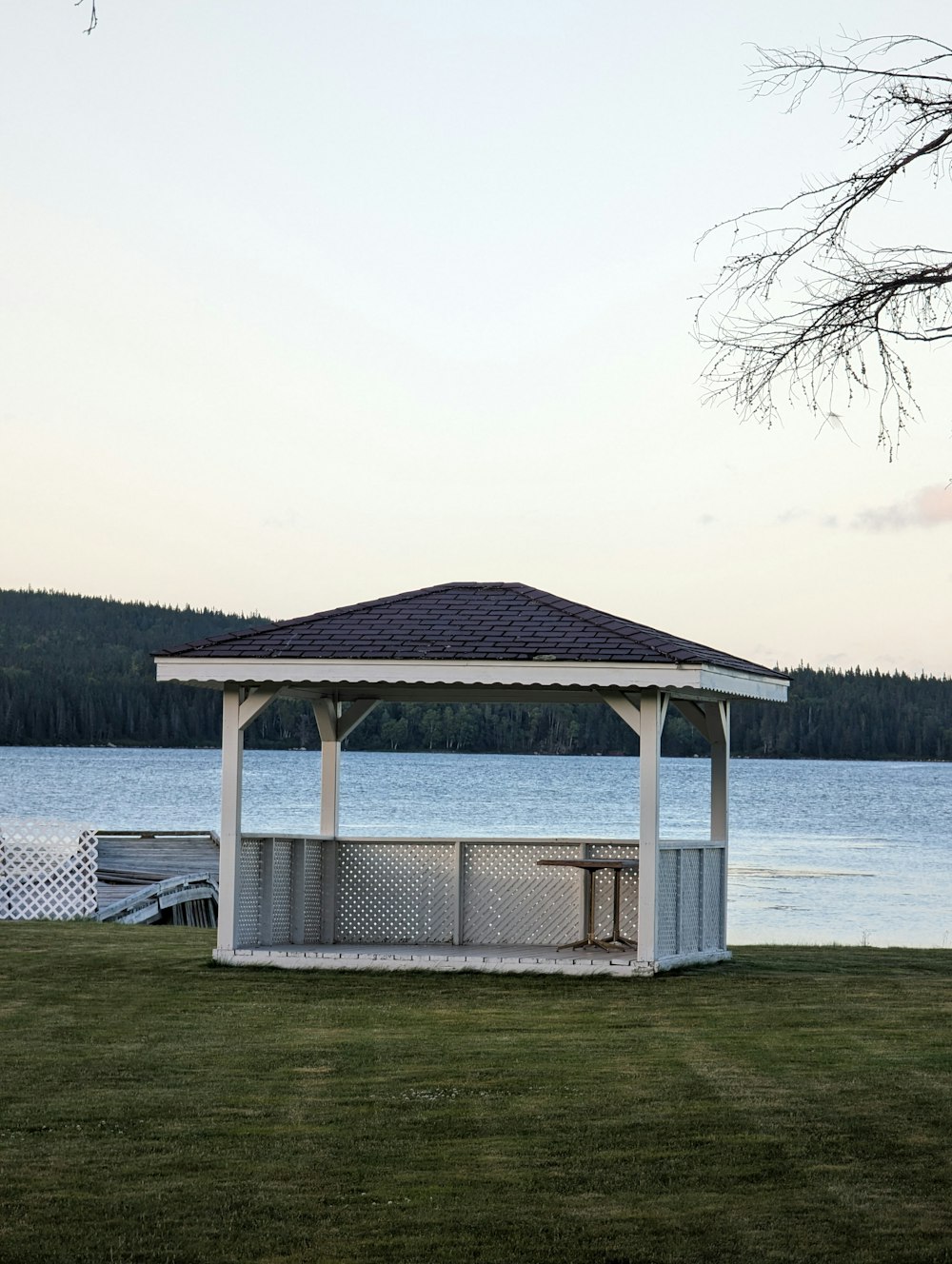 a gazebo sitting on top of a lush green field next to a lake