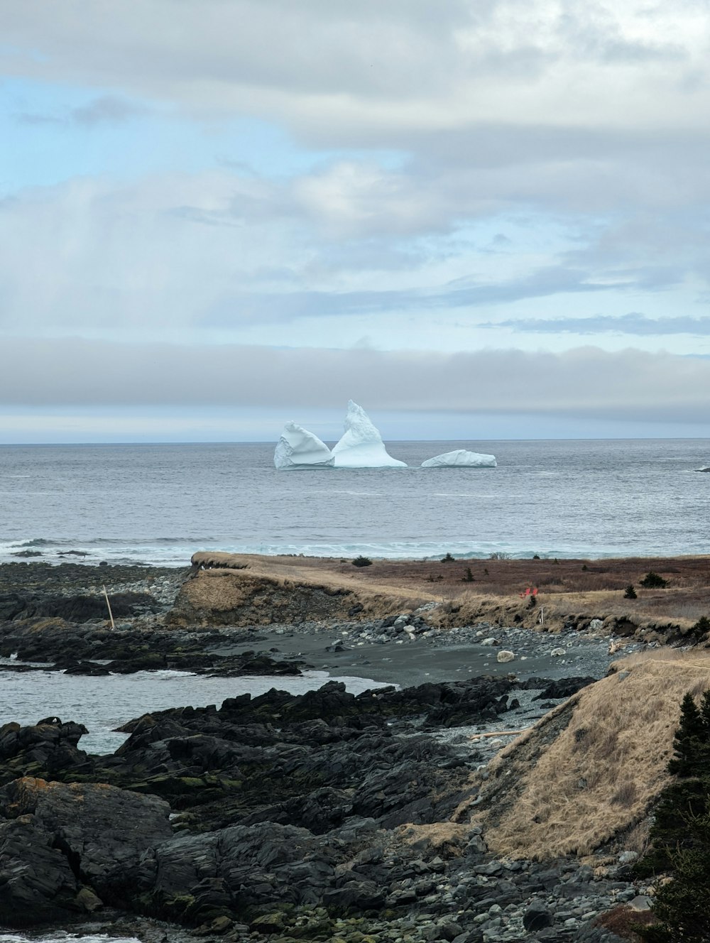 a large iceberg floating in the ocean next to a rocky shore