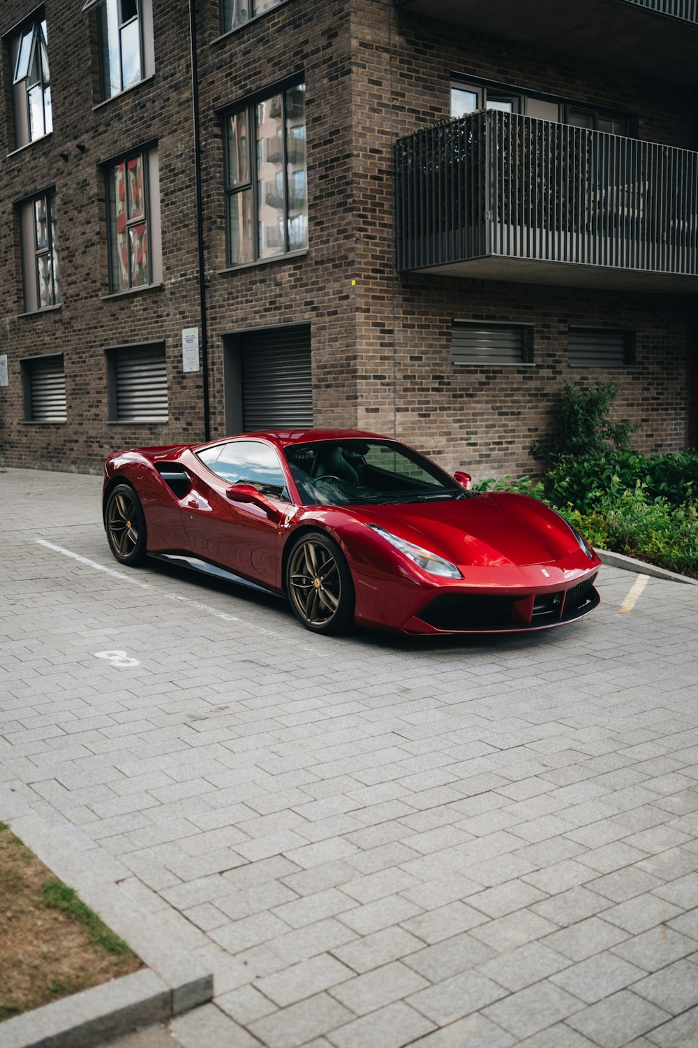 um carro esportivo vermelho estacionado em frente a um prédio de tijolos