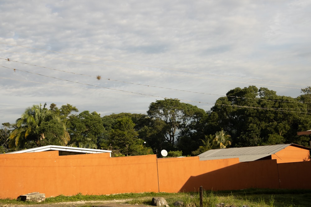 an orange building with a fence and trees in the background
