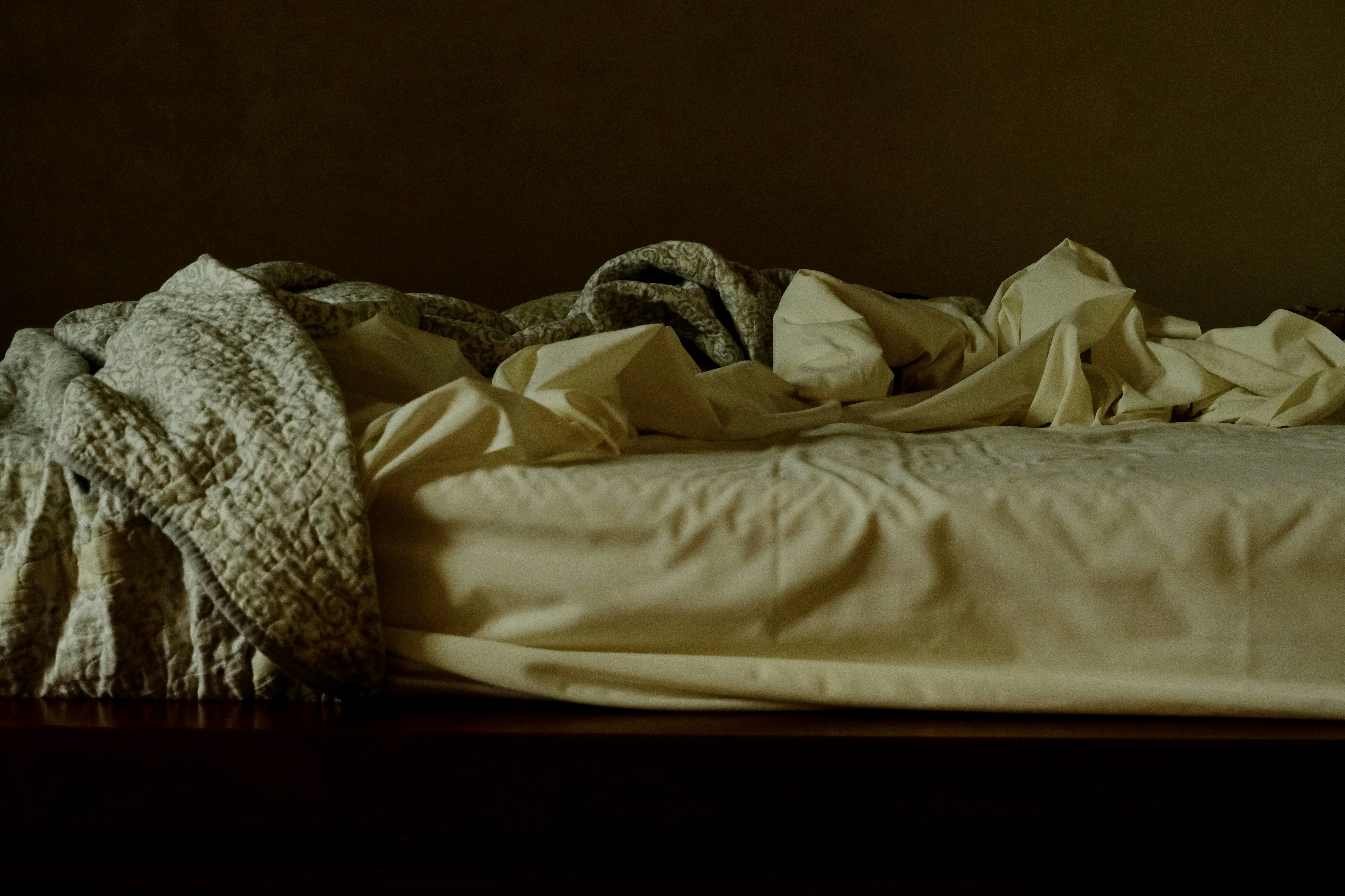 an unmade bed with a blanket on top of it