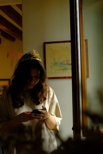 a woman wearing a crown looking at her cell phone