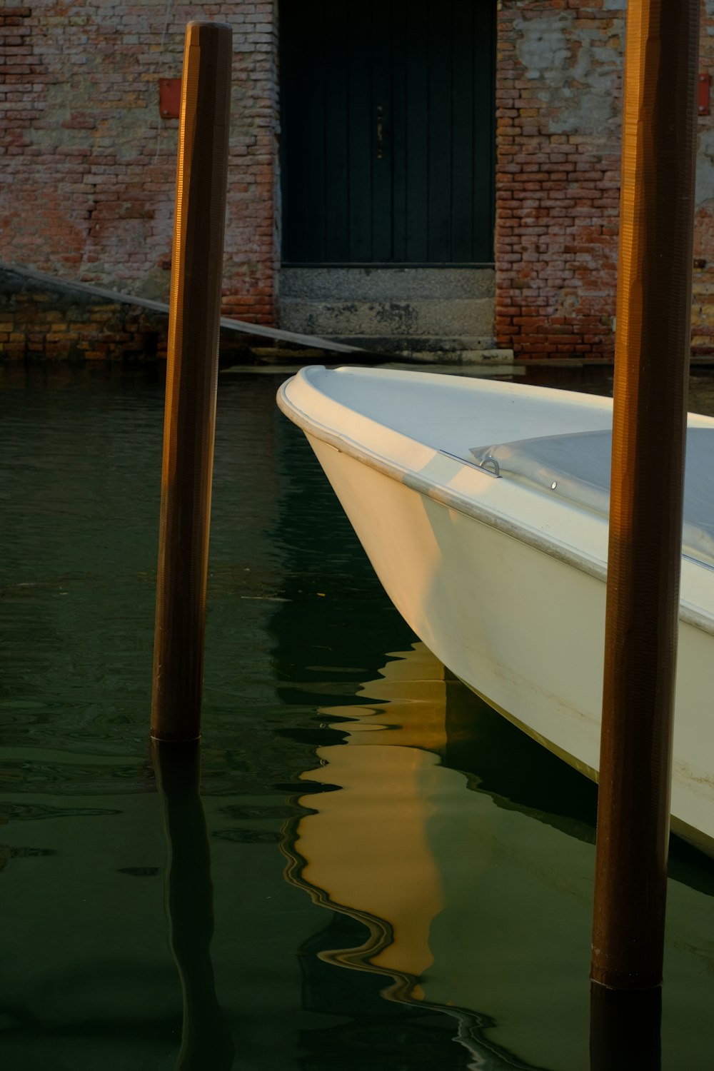 a white boat in a body of water next to a brick building